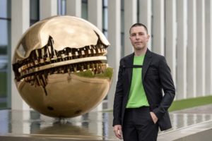 Giorgio Nobili, responsabile marketing, posa accanto alla sfera di Arnaldo Pomodoro